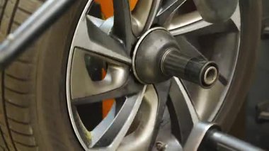 Prag, Çek Cumhuriyeti - 15 Ekim 2025: Tamirci, kurulumdan önce dengeleyici bir makinede dengeleyici araç tekerleğini elle kontrol ediyor. Otomobil servisinde mevsimlik lastik değiştirme işlemi. 