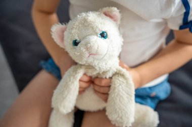 Çocuk iki elinde sıkıca pofuduk bir oyuncak tutuyor. Çocukluğunda rahatlık, güven ve yakınlık sağlayan çok sevilen bir nesneyle duygusal bir bağ. Yüksek kalite fotoğraf