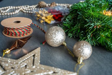 Dekorasyondan önce el yapımı bir Noel çelengi. Etrafı yumuşak odak ile süslenmiş çeşitli şenliklerle çevrili. Geleneksel bir tatil zanaatı için rahat bir ev hazırlığı.