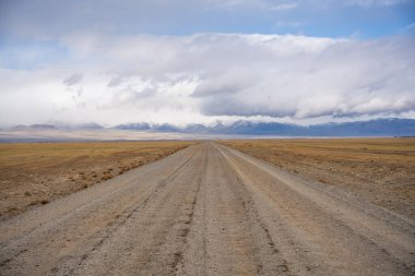 Moğol sınırından Kosh-Agach Altai Rusya 'ya uzak bir dağ manzarasında giden yol. Bozkırda ve iki bölgeyi birbirine bağlayan engebeli arazide manzaralı bir yol. Yüksek kalite fotoğraf