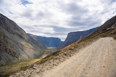 Altai dağlarındaki Katu Yaryk geçidinden geçen çakıl yolu uzak vadiyi yaylaya bağlıyor. Yüksek kalite fotoğraf