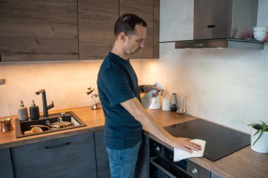 Adam mutfakta soba yüzeyi temizliyor. Günlük temizlik.