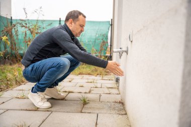 Adam bahçedeki musluğu açıyor. Bahçe bakımı ve mevsimlik hazırlık teması
