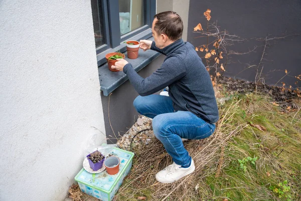 Adam evin yakınındaki bahçede saksı hazırlıyor. Bahar ekimi ve bahçıvanlık hobisi
