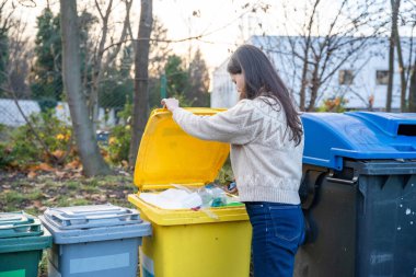 Kadın, umumi geri dönüşüm kutularında ev atıklarını sınıflandırıyor. Açık havada sürdürülebilir yaşam tarzı.