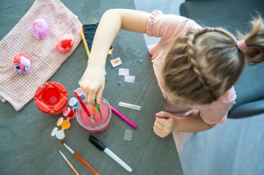 Paskalya yumurtalarını fırça ve renkli boyalarla boyayan çocuk. Yaratıcı Paskalya zanaatı süreci, festival hazırlıkları ve kapalı alanlarda yapılan etkinlikler.