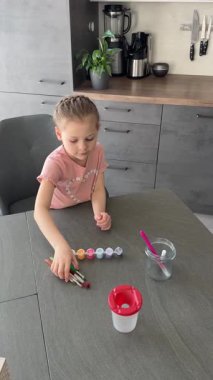 Cam bir kavanoza boya ve fırça koyan bir kız. Paskalya sanatları için hazırlık ve yaratıcı organizasyonu vurgula.