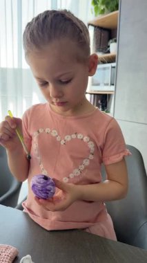 Paskalya yumurtaları üzerinde çalışırken gülümseyen bir çocuk. Sanatsal ifade yoluyla neşe, rahatlık ve gelenek yakalıyor..