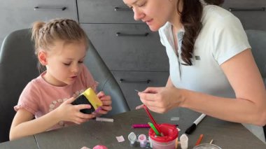 Anne ve kızı evde otururken Paskalya yumurtalarını renkli çıkartmalarla süslüyorlar. Aile Paskalya Sanatları etkinliği, paylaşılan yaratıcılık ve eğlenceli tatil hazırlıkları..