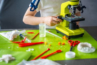 Laboratuvar masasındaki kristal inceleme sırasında mikroskop ayarlayan kız ellerini kapat. Uygulamalı bilimsel çalışma ve ayrıntılı gözlem süreci yoluyla BTMM eğitimi