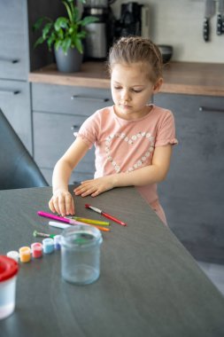 Cam bir kavanoza boya ve fırça koyan bir kız. Paskalya sanatları için hazırlık ve yaratıcı organizasyonu vurgula.