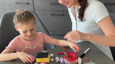 Anne ve kızı evde otururken Paskalya yumurtalarını renkli çıkartmalarla süslüyorlar. Aile Paskalya Sanatları etkinliği, paylaşılan yaratıcılık ve eğlenceli tatil hazırlıkları..