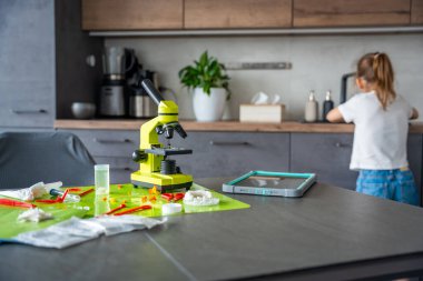 Çocuk arka planda ellerini yıkarken ev bilimi çalışma alanı mikroskop ve aletlerle deneniyor. Sorumlu BTMM öğrenimi ve laboratuvar güvenliği