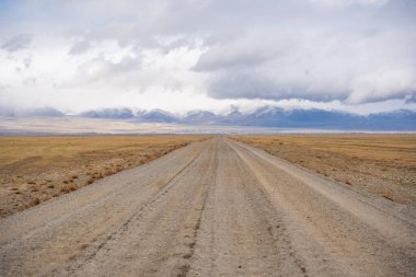 Moğol sınırından Kosh-Agach Altai Rusya 'ya uzak bir dağ manzarasında giden yol. Bozkırda ve iki bölgeyi birbirine bağlayan engebeli arazide manzaralı bir yol. Yüksek kalite fotoğraf