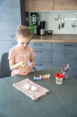 Küçük kız paskalya yumurtasını mora boyuyor. Konsept, evde sanatsal özgürlük ve kültürel bağlılık odaklı.