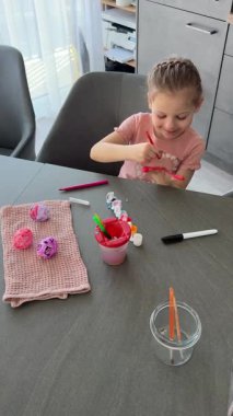 Paskalya yumurtaları üzerinde çalışırken gülümseyen bir çocuk. Sanatsal ifade yoluyla neşe, rahatlık ve gelenek yakalıyor..