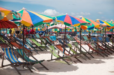 Plaj sandalyeleri ve kumsalda şemsiyeyle