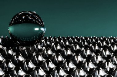 Knurlu yüzeyde yeşil arkaplanda bir cam kürenin yakın görüntüsü