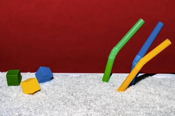 Kırmızı arka planda hayal ürünü beyaz kumsal, pipetli ve tahta küplü.