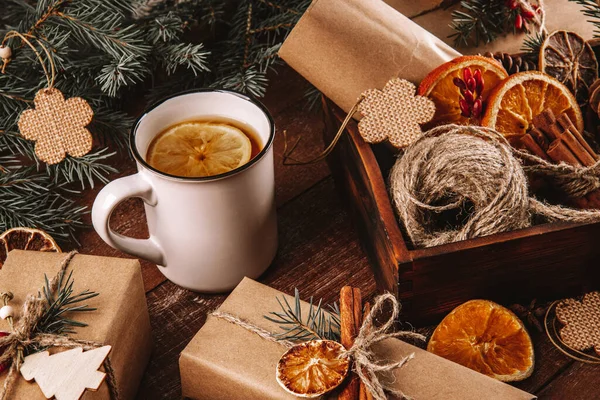  Yeni yıl hediyelerini ahşap bir masaya sarmak için limon ve çevre dostu malzemelerle dolu bir fincan çay. Yüksek kalite fotoğraf