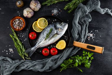Çiğ dorado balığı ve baharatlar, siyah arka planda kızartma tavasında pişirmek için. Yüksek kalite fotoğraf