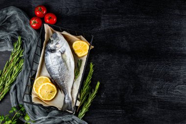 Çiğ dorado balığı ve baharatlar siyah arka planda pişirmek için, üst manzara, yazı için serbest alan. Yüksek kalite fotoğraf