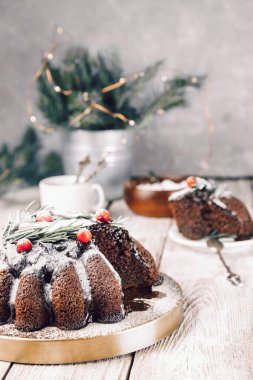Masada böğürtlen ve biberiyeyle süslenmiş Noel çikolatalı pasta, dikey fotoğraf.