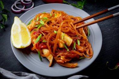  Baharatlı soslu Funchoza ve siyah arka planda kalamar. Bardak erişte, Asya yemeği. Yüksek kalite fotoğraf