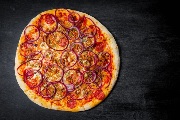 Pizza italiana con salsiccia e anelli di cipolla su sfondo nero, vista dall'alto — Foto Stock