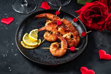  Siyah arka planda kızarmış karides, güller ve şampanya. Sevgililer Günü için orijinal aperatif, romantik akşam yemeği.