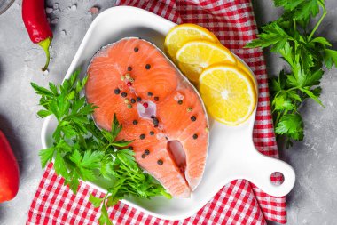  Beyaz bir tabakta çiğ somon bifteği. Hazırlanması için baharatları var. Yakın plan çiğ kırmızı balık.