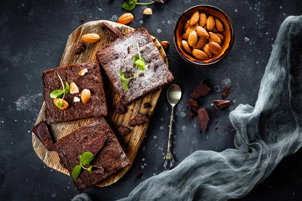 Trozos de brownie de chocolate casero con hojas de menta y nueces en el fondo gris, vista superior — Foto de Stock