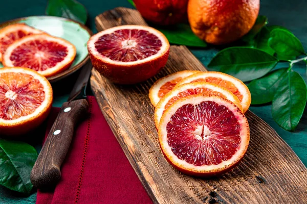 Red bloody orange cut into slices on a wooden cutting board close up