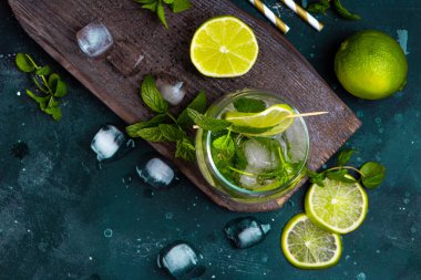 Mojito 'yu limonlu, naneli ve buzlu bir bardakla koyu bir arka planda yeniliyorum. Soğuk yaz kokteyli
