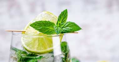 Web afişi. Mojito 'yu limon, nane ve buzla tazeleyip beyaz arka planda bir bardakta kapatıyoruz. Mesaj için boş yer var. Soğuk yaz kokteyli