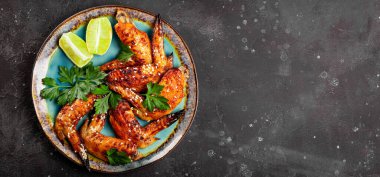 Web afişi. Susam tohumlu fırında tavuk kanadı, maydanoz ve limon tabakta, yazı için boş yer var.