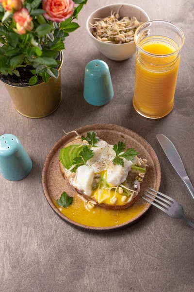 Lehká letní snídaně - sendvič s avokádem, tvarohem, naklíčenými fazolemi a vařeným vejcem s pomerančovým džusem na stole — Stock fotografie
