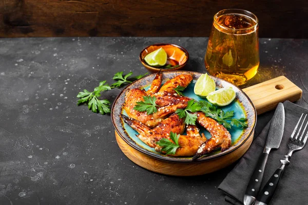 Susam tohumlu fırında tavuk kanadı, bir tabak maydanoz ve limon ve masada bir bardak bira seçici odak noktası, metin için kopyalama alanı