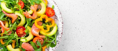 Taze yaz sebze salatası, roka, domates, dolma biber, avokado ve somon tabakta yakın bir tabakta, web sitesi için metin alanı için afiş