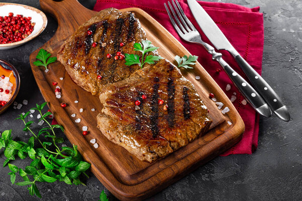 Two beef steaks cooked on the grill on a wooden cutting board close up. High quality photo