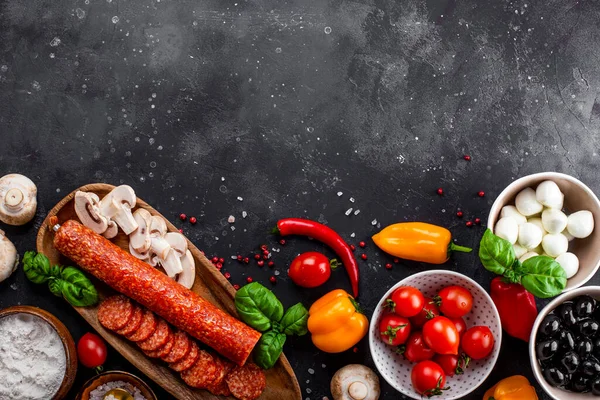  Koyu gri arka planda pizza malzemeleri, mesaj için boş yer. Pepperoni sosisi, mozzarella peyniri, domates, zeytin, mantar ve un pizza ve makarna yapmak için farklı ürünlerdir.