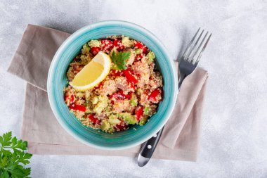  Domatesli somon salatası, avokado ve kinoa açık gri bir masada mavi bir kasede, bir tabak dengeli beslenme üst görünümü.