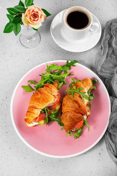 Croissants avec roquette, avocat et saumon, une tasse de café noir et un verre de jus d'orange sur la table, concept de petit déjeuner photo verticale — Photo