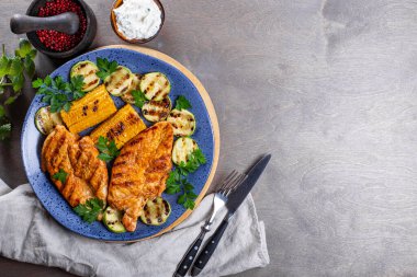 Mavi tabakta mısır ve kabakla ızgara tavuk göğsü. Kızarmış tavuk ve sebzeli yaz yemeği. Metin için kopyalama alanı olan fotoğraf