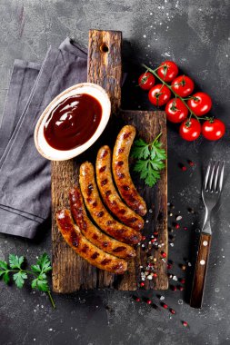  Izgara kıyma ve barbekü soslu domuz sosisi ahşap kesim tahtasının üst tarafında dikey fotoğraf.