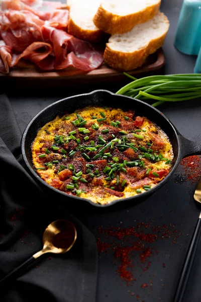 Omelette d'oeuf avec saucisse et assaisonnements dans une casserole en fonte close up, photo verticale avec mise au point douce — Photo