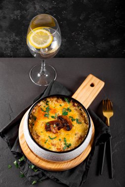 Julienne yanında patates ve mantarla birlikte karanlık bir arka planda, dikey bir fotoğrafta. Geleneksel Fransız yemeği