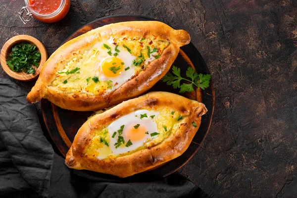  Geleneksel bir Gürcü yemeği, peynirli ve yumurtalı Adjarian khachapuri ve arka planda baharatlı domates sosu.