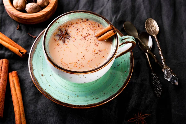 Keten masa örtüsü üzerinde süt ve baharatlı geleneksel Hint çayı, üst manzara. Masala chai, kapat.
