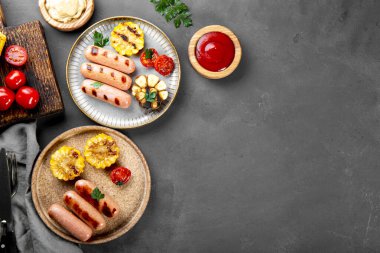  Grilled sausages with vegetables and sauces. Summer BBQ with sausages, corn and tomatoes. Top view, copy space for text